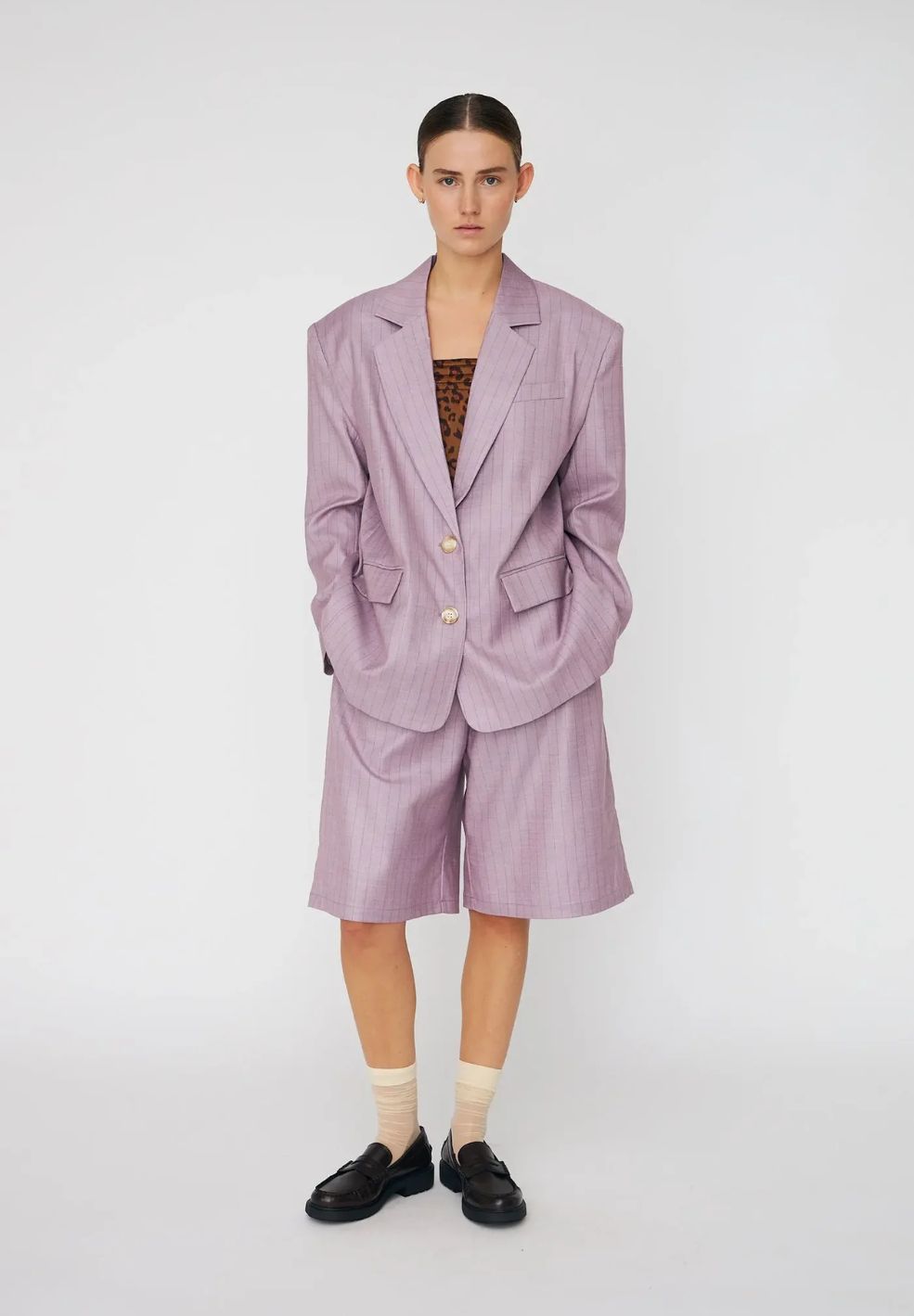 Person wearing a light purple suit with shorts on a white background
