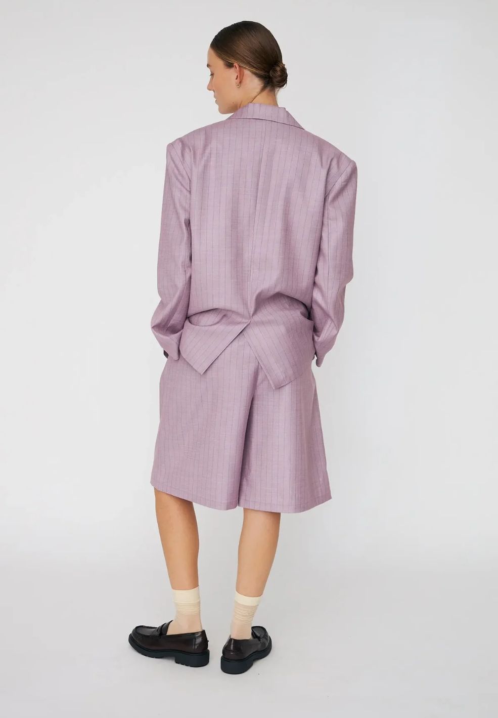 Person wearing a matching purple outfit with a shirt and shorts on a white background