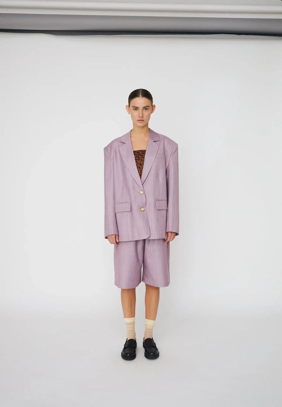 Person wearing a light purple suit with a plain background