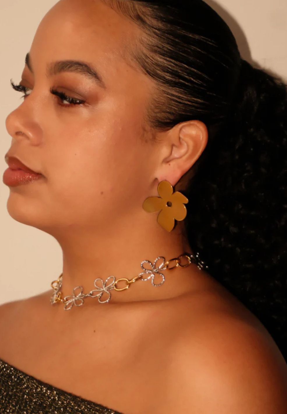 Bloomed Necklace: Mixed metal chain with gold and silver flower pendants, worn by a woman.